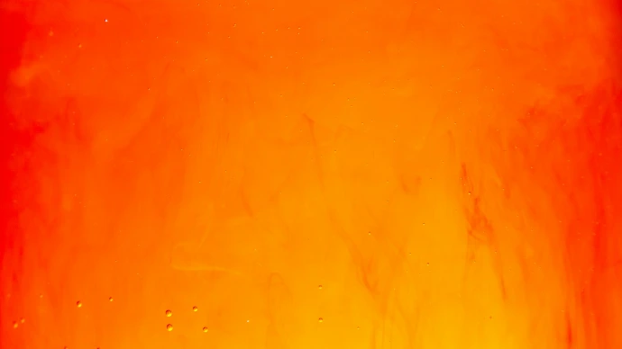 Red and orange ink swirling in clear liquid with small air bubbles